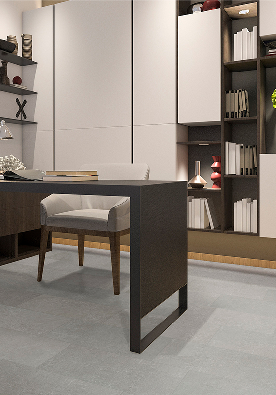 Modern office space with a sleek black desk, beige upholstered chair, and built-in shelves filled with books and decorative items. The room features light gray flooring and a neutral color palette.
