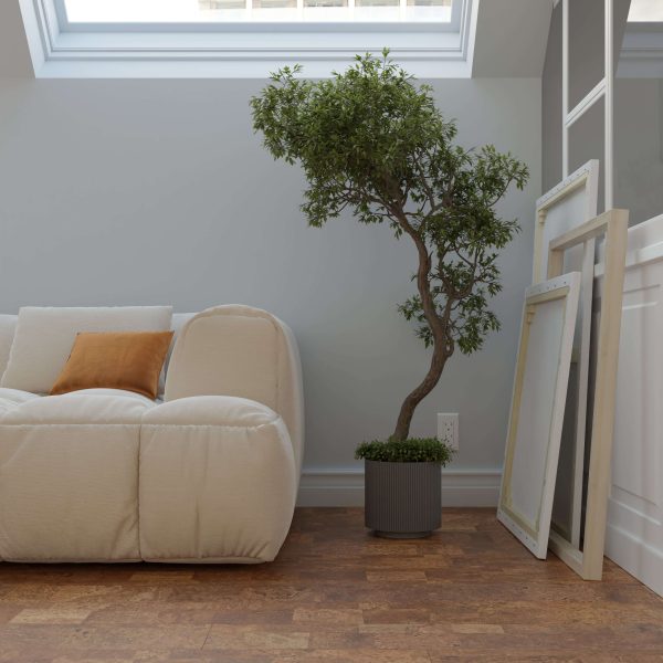 A cozy room with the Boulevard Natural white sofa, an orange pillow, a potted tree, and two empty picture frames leaning against the wall under a skylight.