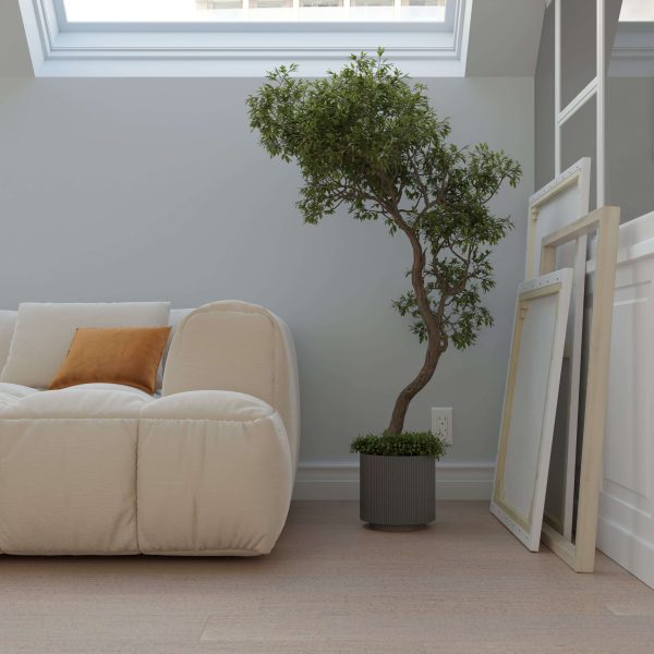 A modern, minimalist living space features the Paseo Merida white sofa, an orange pillow, a tall potted tree, and several empty picture frames leaning against a white wall beneath a skylight.