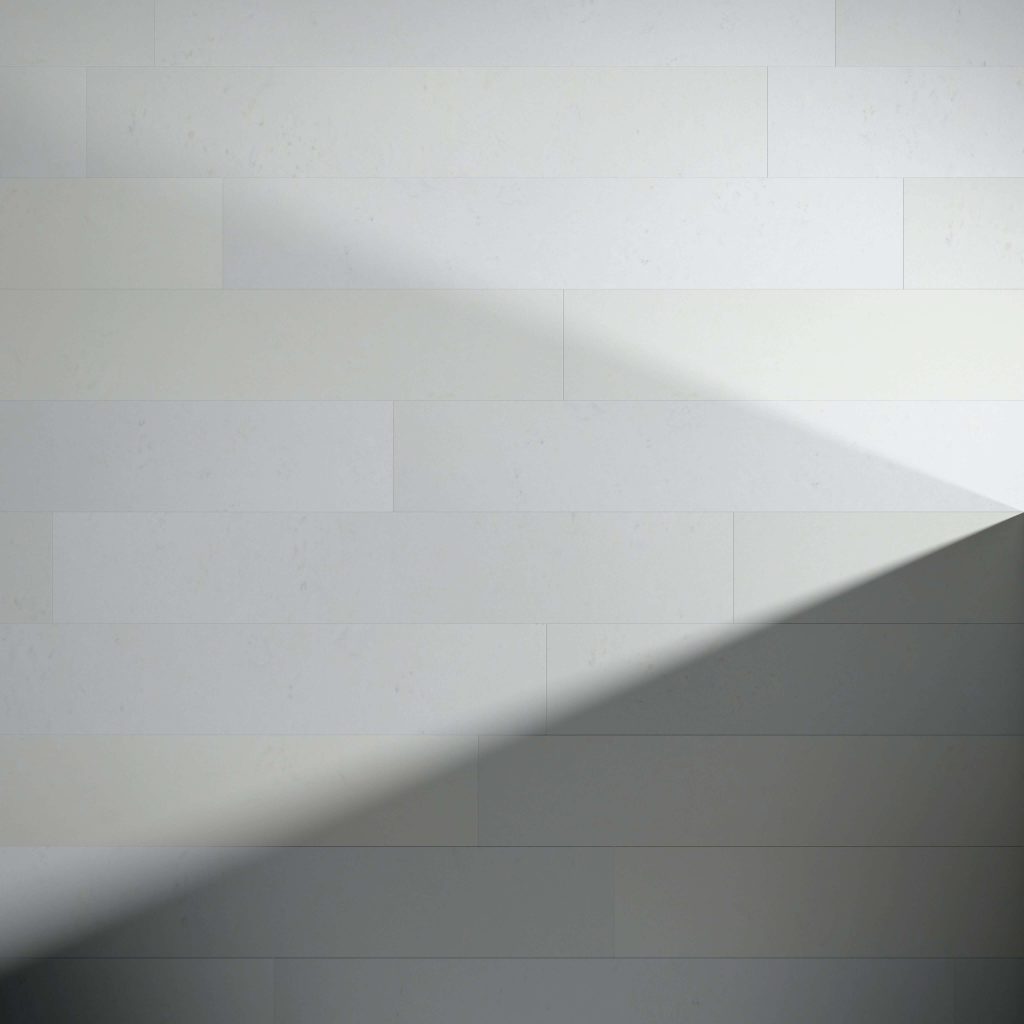 Burl African Ivory tiles form a plain, light-toned wall where a diagonal shadow creates a triangular divide between bright and shaded sections.