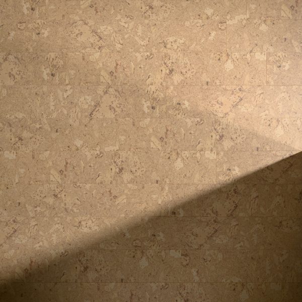 A diagonal beam of light partially illuminates the Burl Natural wall, highlighting its textured beige surface and subtle marbled pattern while casting a soft shadow across it.