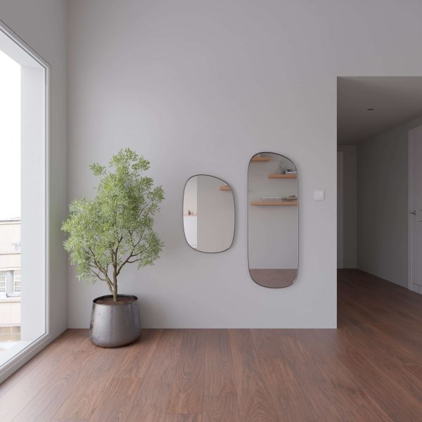 A minimalist room with light gray walls, an Adirondack Oak wooden floor, a potted plant, two oval mirrors on the wall, and a large window letting in natural light.