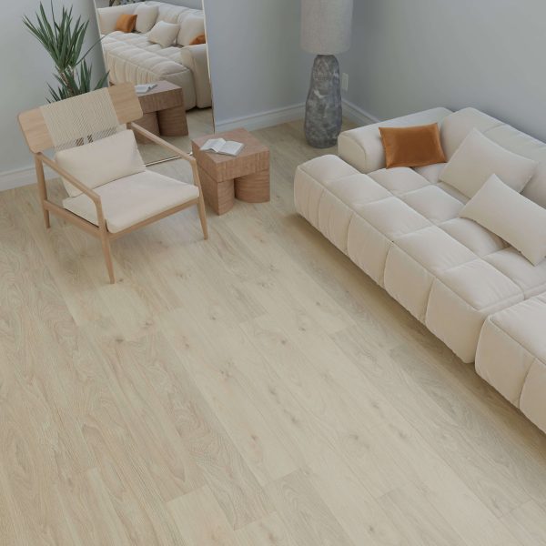 A minimal living room featuring the Peyto beige cushioned sofa, light wood flooring, a woven-back wooden chair, two compact wooden side tables, a tall lamp, potted plant, and large mirror against a light gray wall.