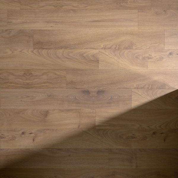 Woolley* light brown wooden floorboards feature a natural grain pattern with subtle texture and visible knots, partially shaded by a diagonal shadow across the lower right corner.