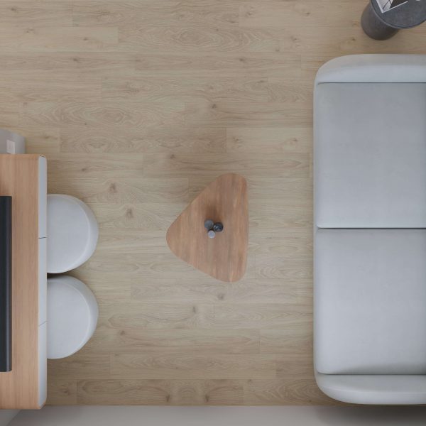 The Athabasca features a minimalist living room with a light wood floor, white sofa, small triangular wooden coffee table holding two bottles, and part of a desk paired with two round white stools—seen from above.