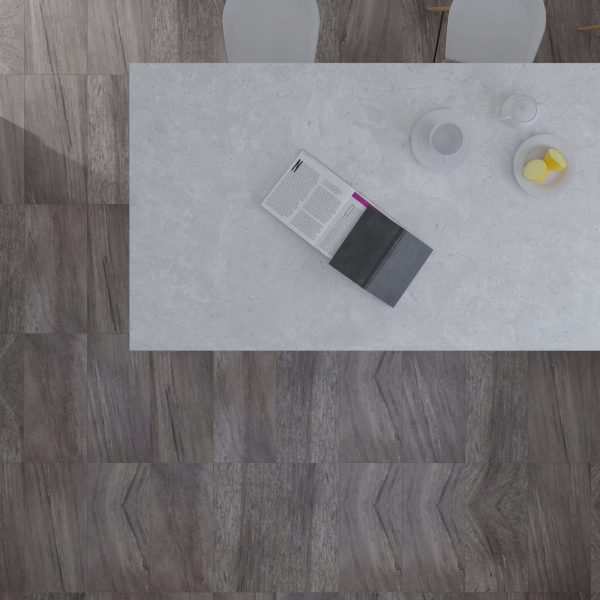 A white table with an open magazine, closed book, cup, saucer, and plate with lemon slices is seen from above on Cenere Grey tiles beside two white chairs.