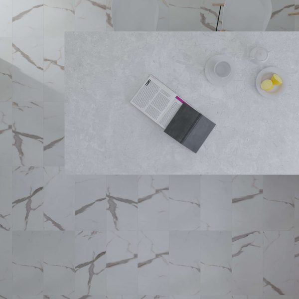 A Calcatta* marble-tiled floor and a light gray stone table with an open book, white teapot, cup, and a bowl of three lemons seen from above; two white chairs are partly visible at the top.