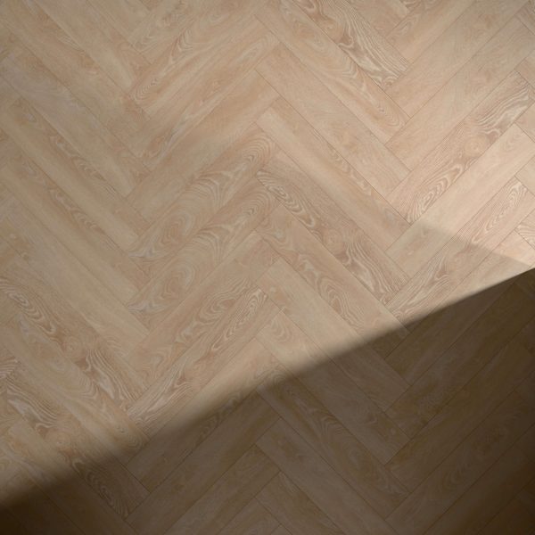 Shelbourne light wood flooring in a herringbone pattern displays subtle grain details and a natural, warm tone, with a diagonal shadow partially covering the bottom right corner.