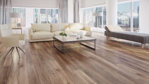 A modern living room with large windows, light-colored sofas, a chaise lounge, an everwood designer coffee table, hardwood floors, and city buildings visible outside. Natural light fills the space.