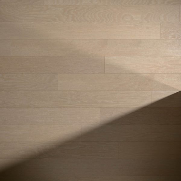 Light and shadow form a diagonal line across Basin Oak's wooden floor, highlighting its natural grain patterns and dividing the image into a brighter upper section and a darker lower right section.