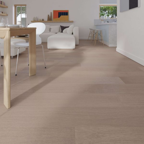 A modern living and dining area features Solano Oak R&Q* flooring, a wooden dining table, white chairs, a white sofa, minimalist decor, large windows for natural light, and a visible kitchen in the background.