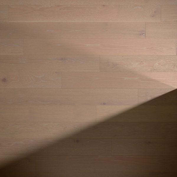 Basin Rustic Oak* flooring features light wood with visible grain and subtle knots, a smooth and clean surface, and natural color and texture variations. A diagonal shadow partially covers the lower right corner.