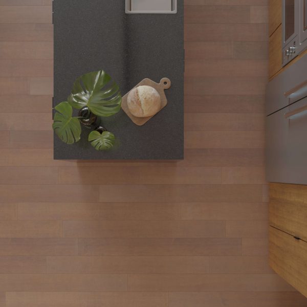 Top-down view of a kitchen countertop in Maple Arabica* finish, featuring a loaf of bread on a wooden board and a green leafy plant by the sink, with matching wooden cabinets and flooring.