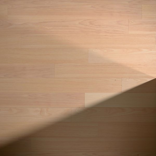 Hickory Natural* features light-colored wood planks arranged horizontally, with sunlight casting a diagonal shadow across the lower right corner for striking contrast between illuminated and shaded areas.