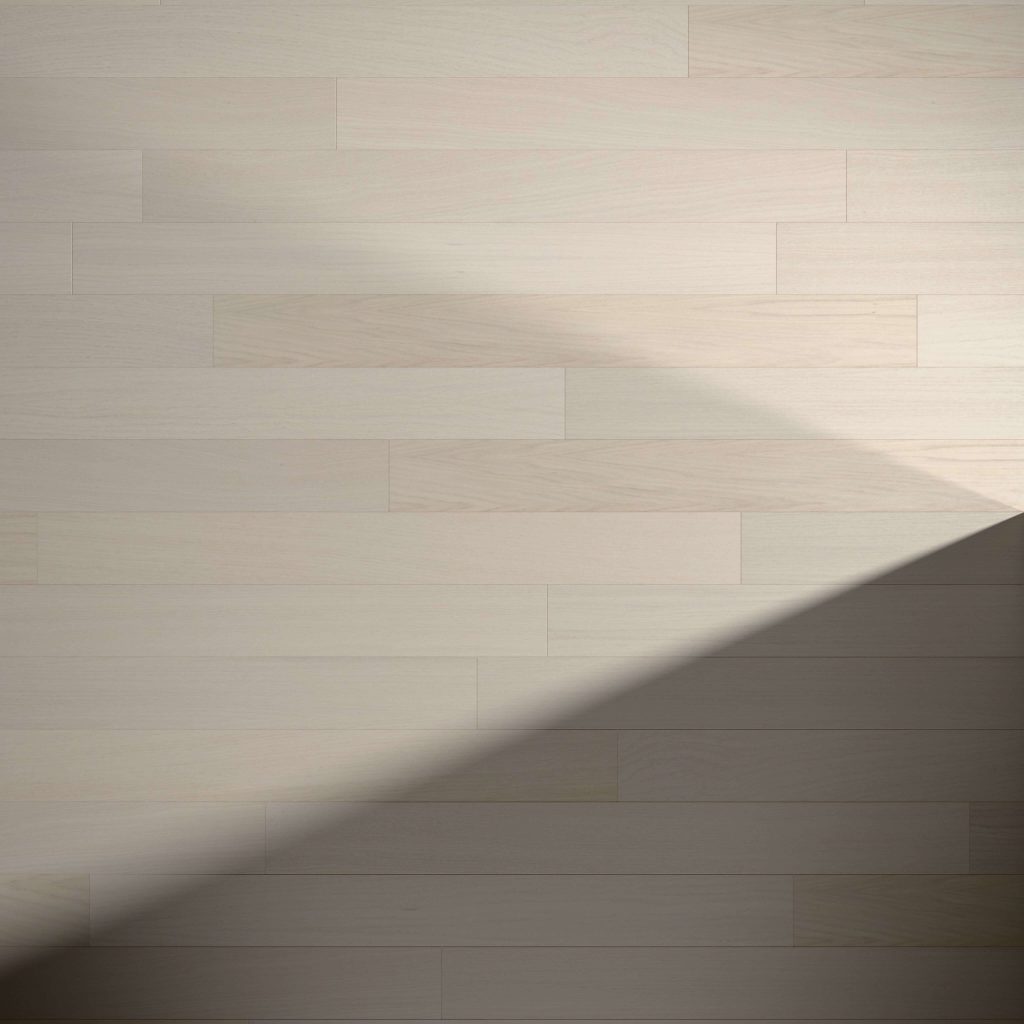 Alabaster Oak* features light-colored, long horizontal planks with a clean, smooth finish. A diagonal shadow crosses the bottom right corner, highlighting the contrast between illuminated and shaded sections of the floor.