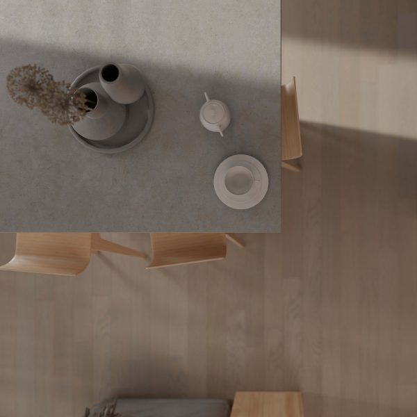 A minimalistic table setting viewed from above, showcasing a gray tabletop with a vase, teapot, cup and saucer, and wooden chairs on Pebble Oak* flooring.
