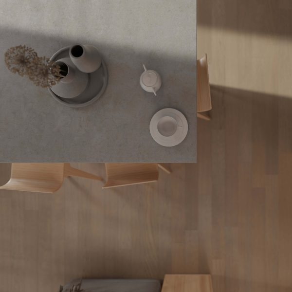 A minimalist table setting features a gray vase, bowl on a tray, white teapot, and cup and saucer. Light wooden chairs sit around a Cortland Oak* floor, viewed from above as natural light casts soft shadows.