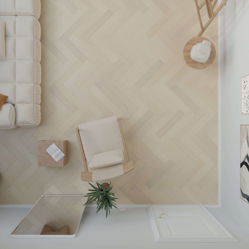 Top-down view of a minimal living room with Coastal Oak* (Left) herringbone wood floor, beige sofa, armchair, small table, potted plant, ladder shelf, and abstract wall art. Sunlight streams in from a window.