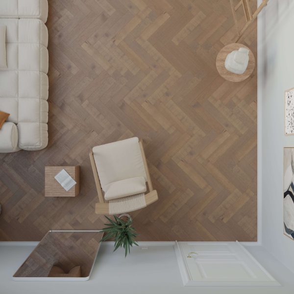 Top-down view of a living room featuring Maple Arabica* (Right) herringbone wood flooring, a beige armchair and sofa, a side table, a plant, and a white door. Warm neutral tones and minimalist décor create an inviting space.