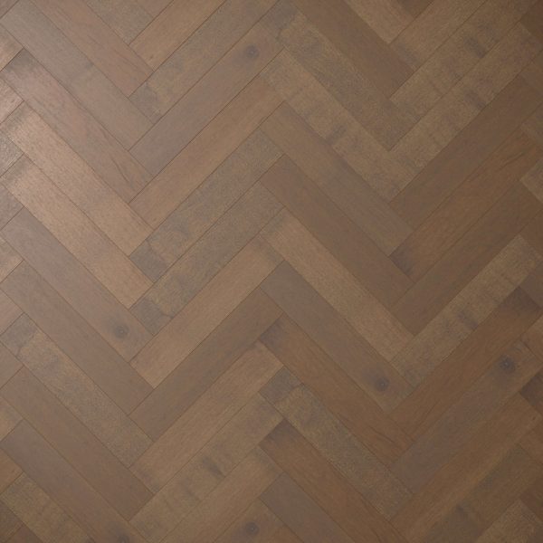 Close-up of Maple Arabica* (Right) wood flooring in a herringbone pattern, featuring medium to dark brown planks arranged in a zigzag design and highlighting the wood’s natural grain and texture.