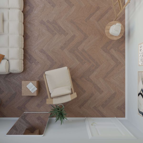 Top-down view of a modern living room featuring Harvest Walnut* (Right) herringbone floor, a beige armchair, small wooden table, tufted couch, potted plant, wall art, partial door, and rug.