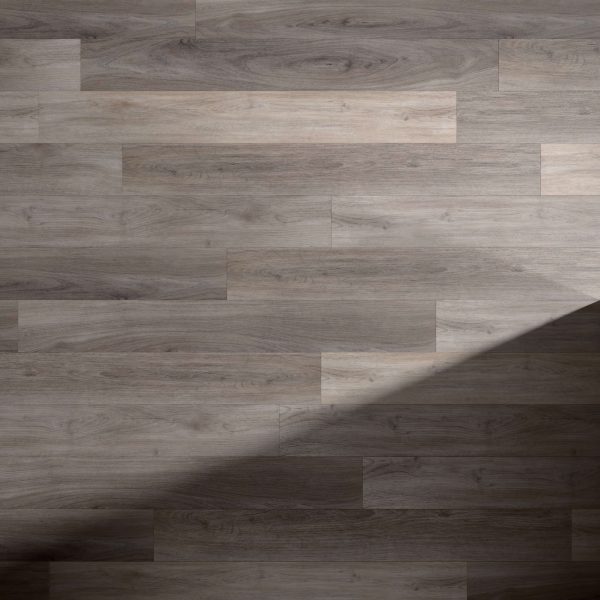 Tokyo Oak* features a light brown wooden floor with a subtle wood grain pattern. A diagonal shadow crosses the lower right corner, highlighting the contrast between illuminated and shaded areas on the Tokyo Oak* surface.