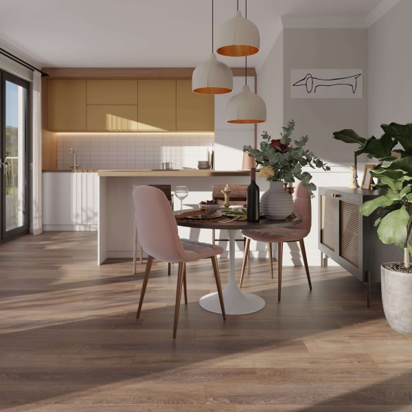 A modern kitchen and dining area with Sydney Oak* floors, a round table for two, pink chairs, pendant lights, indoor plants, and sunlight streaming through glass doors. Minimalist artwork decorates the light-colored wall.