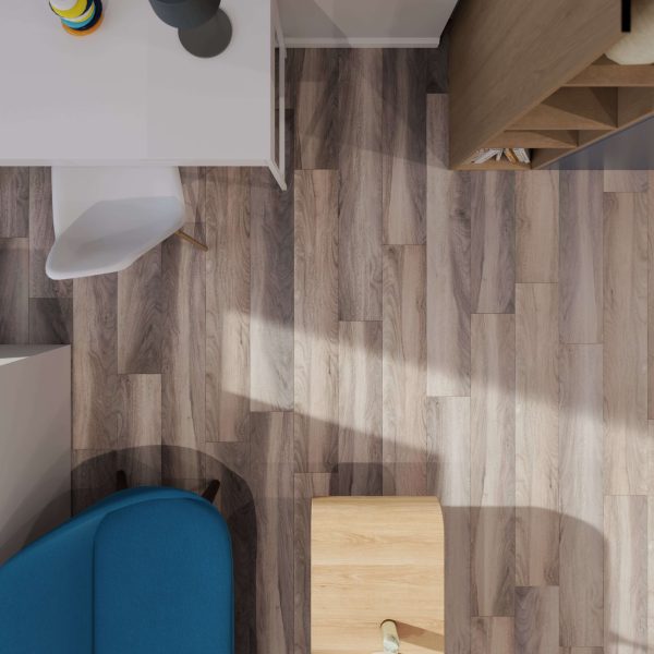 Top-down view of a modern room featuring Rio Walnut* wood flooring, a white desk and chair, blue sofa, wooden bookshelf, and small wooden table with lamp. Natural light casts soft shadows across the floor.