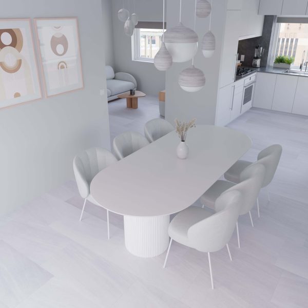 Minimalist dining area featuring a Tidal Grey oval table, six modern upholstered chairs, pendant lights, abstract art, and an open view into a bright kitchen and living room with large windows.