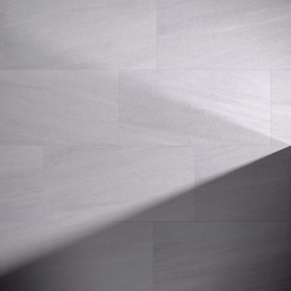 Tidal Grey* tiles with a smooth texture are laid horizontally. A diagonal shadow crosses the lower right corner, highlighting the contrast between light and dark on the tiled surface.