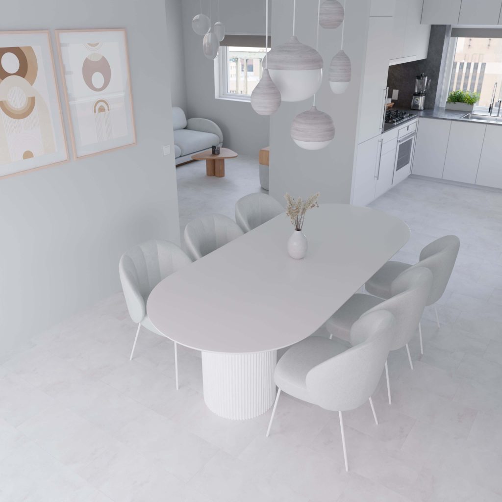 The Capri* features a minimalist dining area with a white oval table, six light gray chairs, and modern pendant lights. Abstract art decorates the wall while the sleek, neutral-toned kitchen and living space are visible in the background.