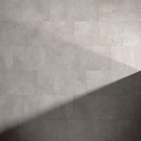 Modena* gray rectangular tiles cover the wall, featuring a subtle mottled texture. A diagonal shadow falls across the lower right, highlighting the contrast between illuminated and shaded areas.