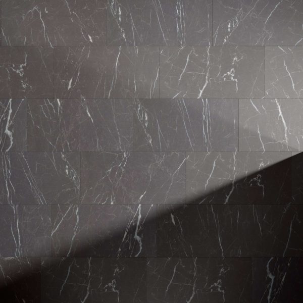 Nero rectangular dark gray marble tiles with white veining are laid horizontally, with a diagonal shadow over the lower right corner highlighting the contrast between illuminated and shaded surfaces.