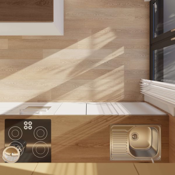 Top-down view of a modern kitchen counter featuring the Thorncrest electric stove, a stainless steel sink, and sunlight casting shadows across light wood surfaces. A large window appears to the right.