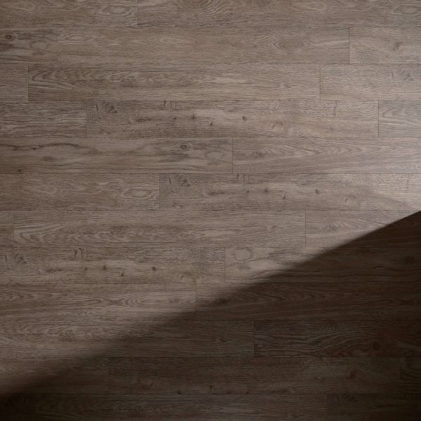 Foremast medium brown wooden floor featuring a subtle wood grain pattern, lit from the top left with a diagonal shadow from the bottom right, indicating light from a nearby window or source.