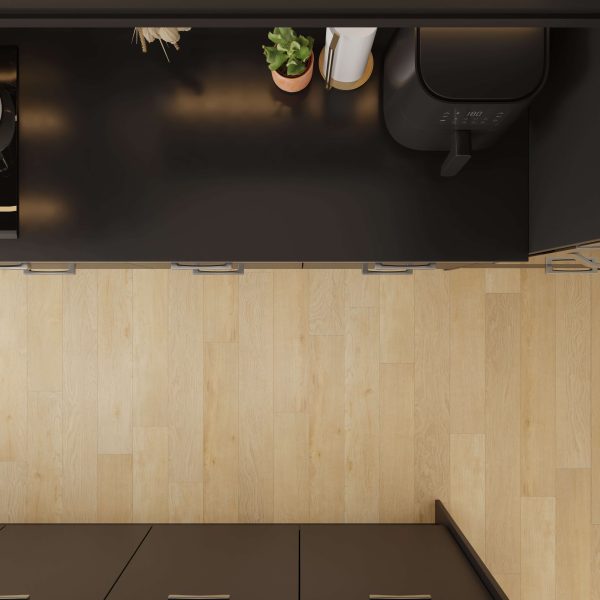 Overhead view of a modern kitchen with a potted plant, paper towel roll, small appliance, and Deck Oak light wood flooring. Dark cabinets frame the top and bottom of the image.