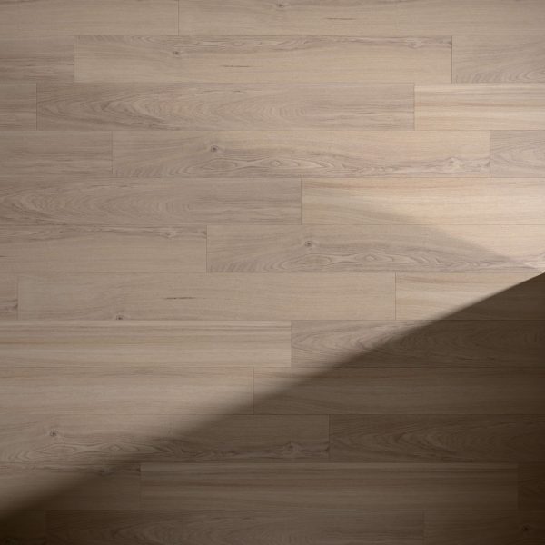 Helm Oak light brown wooden floor features a clear grain pattern. A diagonal shadow crosses the bottom right corner, highlighting the contrast between the illuminated and shaded areas of this flooring.