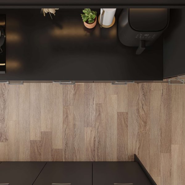 A top-down view of a kitchen countertop featuring a small potted plant, a paper towel holder, and a black air fryer, with Lido Oak* light-colored wooden flooring visible below.