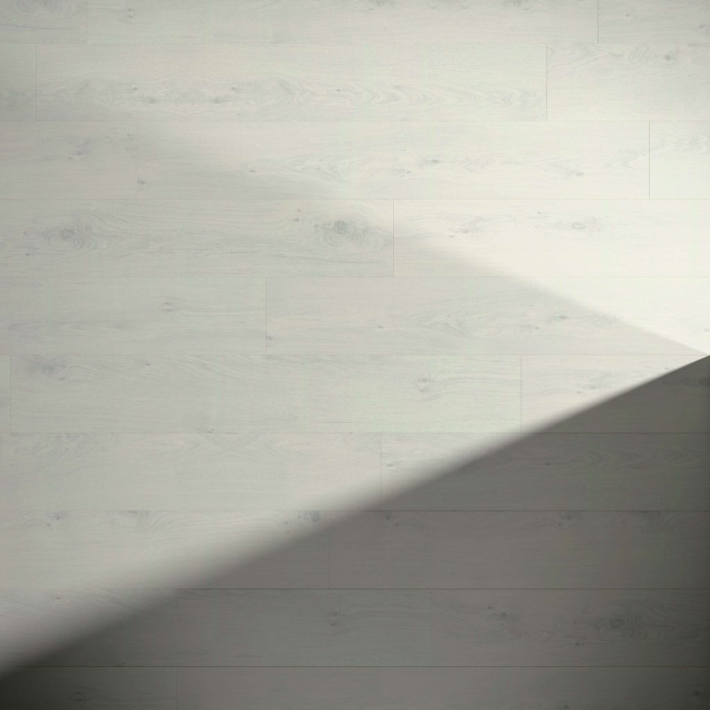 Paloma Oak features a light-colored wooden floor with subtle natural grain patterns. A diagonal shadow crosses the lower right side, highlighting the contrast with the brighter upper area.