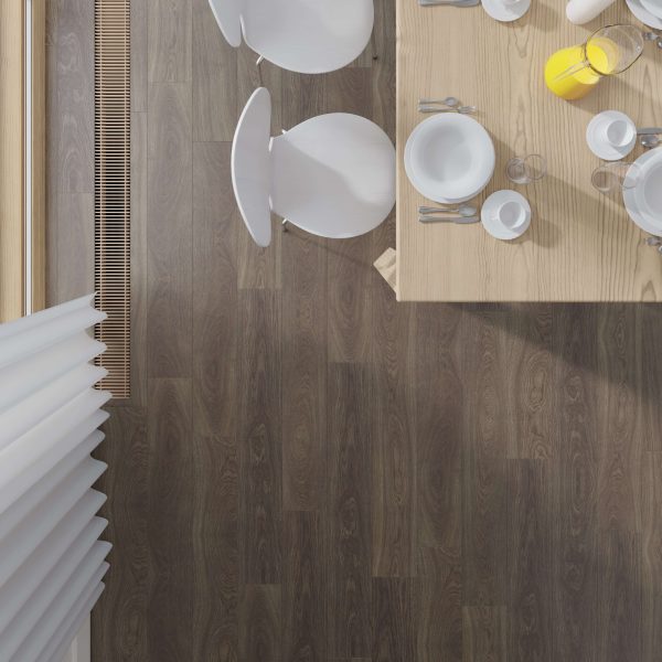 A top-down view of an Alexandria Oak dining table set for three with plates, cups, cutlery, and a glass jug of orange juice. Three white chairs surround the light wood table on a dark wood floor near a large window.