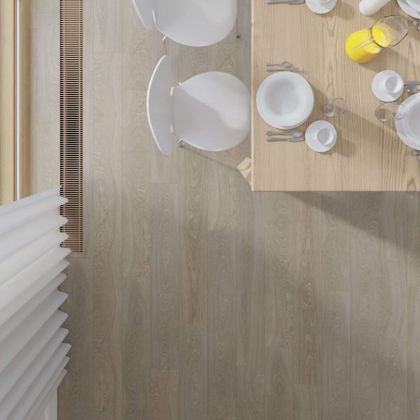 Top-down view of a Langley Oak dining table set with white plates, cups, cutlery, and a pitcher of orange juice. Two white chairs sit by the table on a light wood floor.