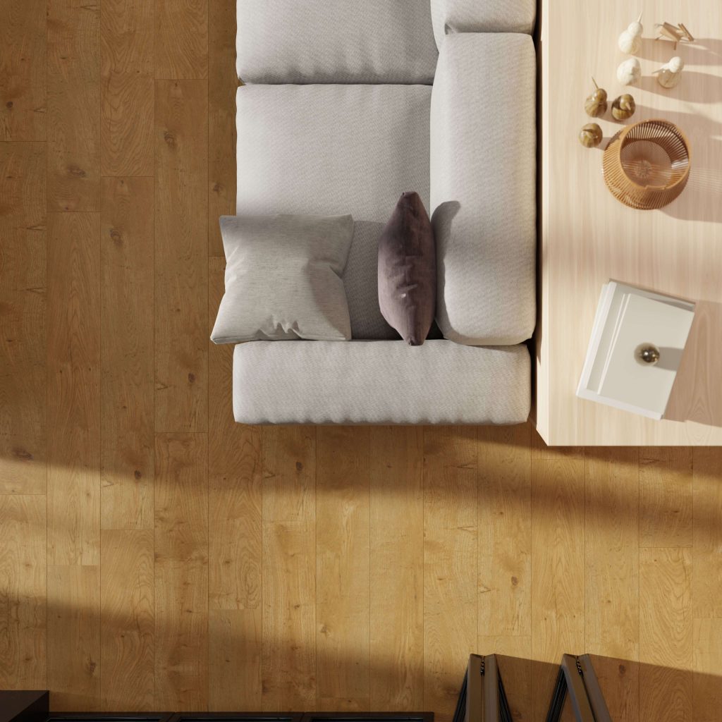Top-down view of a light gray sofa with two pillows beside a light wooden coffee table with decor. The floor features Annapolis Oak, while soft sunlight casts gentle shadows across the scene.