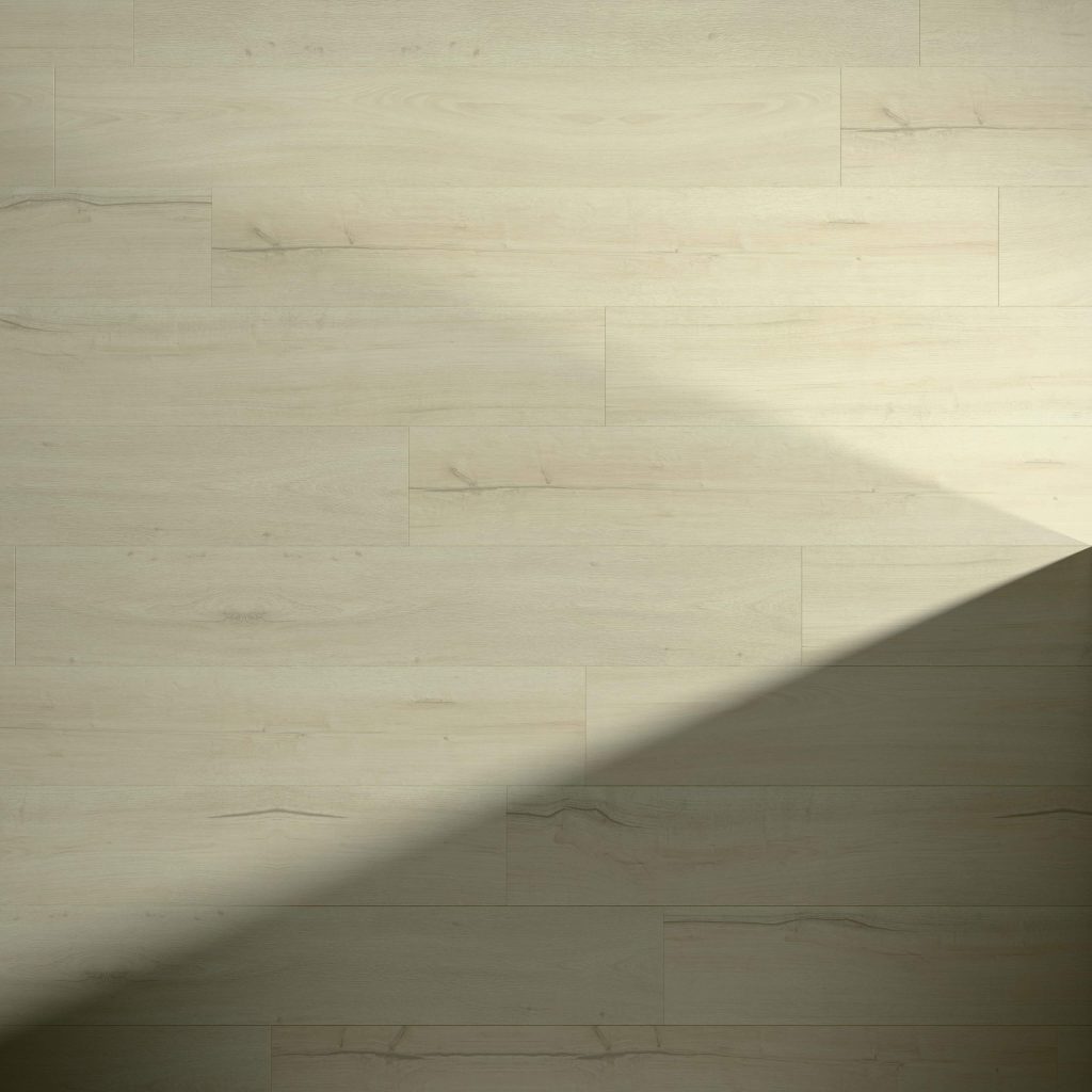 Galena Oak light wood flooring features subtle grain and natural markings. A diagonal shadow crosses the lower right corner, highlighting the contrast between illuminated and shaded areas. Floorboards are arranged in a staggered pattern.