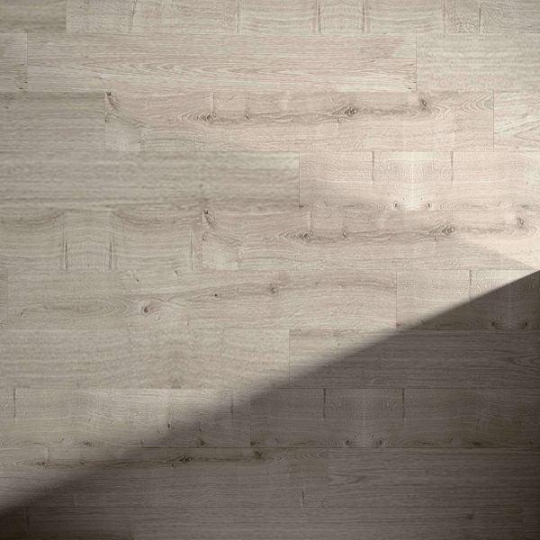 Laurel Oak flooring with a diagonal shadow stretching from the lower right corner to the center, highlighting the contrast between sunlit and shaded areas. Wood grain and plank patterns are clearly visible.
