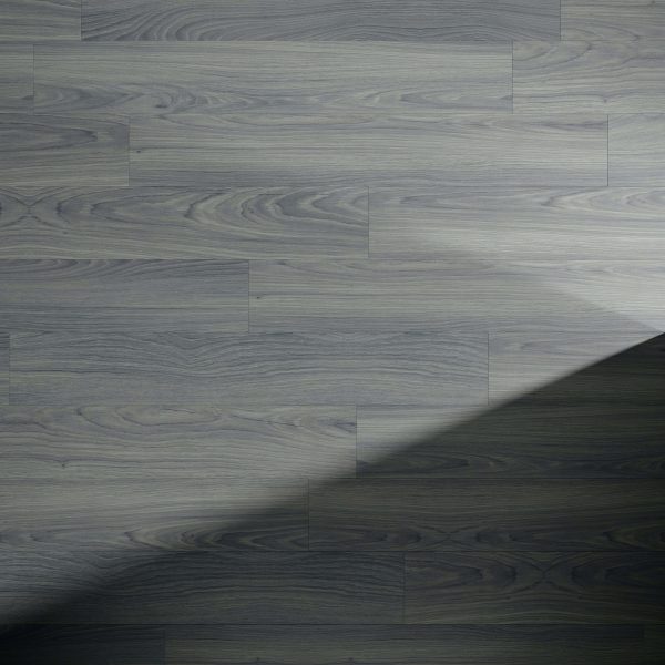 A section of Ventura Oak gray wooden flooring with a diagonal shadow across the lower right corner, emphasizing the wood grain and plank pattern.