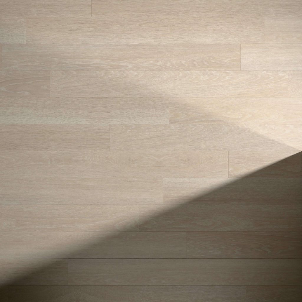 Estate Oak Beige flooring features a light wood tone with a diagonal shadow cast from the bottom left to the right, highlighting a striking contrast between illuminated and shaded areas.