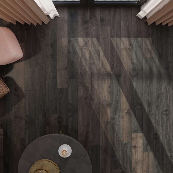 Overhead view of a Newcastle Oak Dark floor with sunlight streaming through window blinds, casting geometric shadows. A round table, part of a pink chair, and a wicker basket are partially visible in the corners.