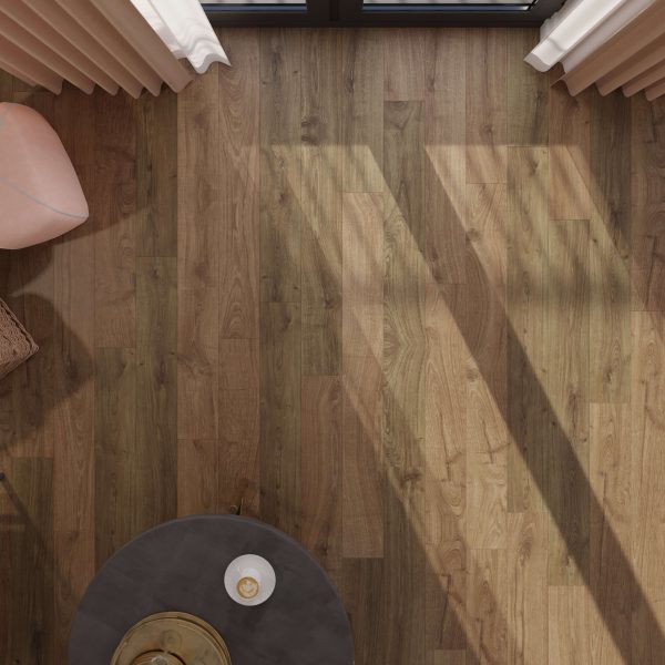 A top-down view of a sunlit Newcastle Oak Brown floor casts long shadows, featuring a small round table with a cup and saucer, a woven basket, and the edge of a pink chair near cream-colored curtains.