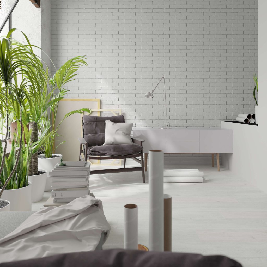 A bright, airy living room featuring a Laneffe Oak sideboard under a sleek lamp, complemented by a gray armchair, white cushions, white brick wall, potted green plants, and rolled-up papers. The modern decor exudes minimal elegance.