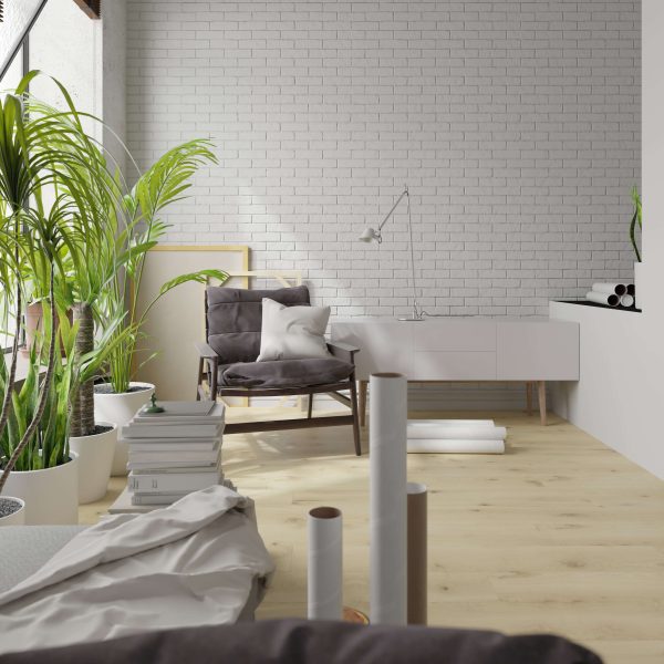 Bright, modern room featuring Kortemark Oak flooring, white brick walls, potted plants, a cushioned chair with pillows, a white sideboard, and art supplies—perfect for a creative or relaxing workspace.